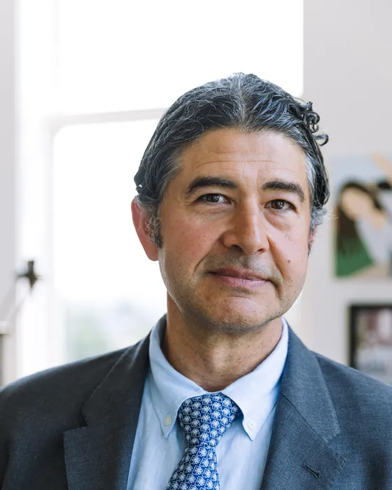 Portrait of Dr. Rod Oskouian in a grey suit and a blue patterned tie, in his office
